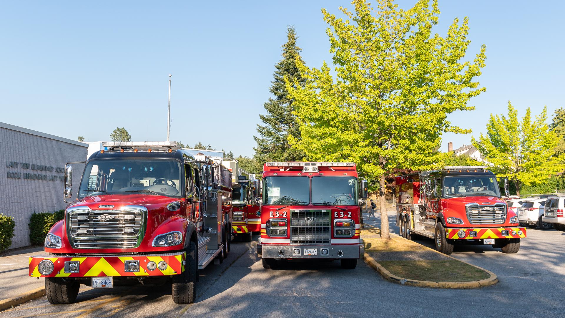 Three different varieties of fire trucks are parked on a street for display.