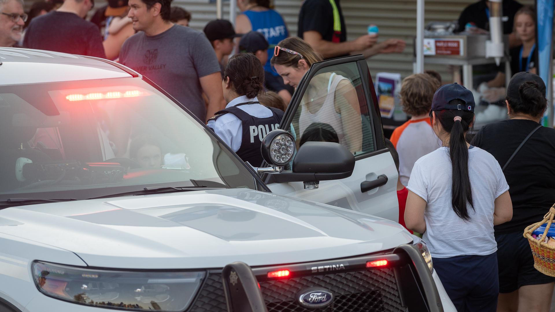 A police car with its lights on sits at the 2022 Hot Summer Nights Event where the police are participating.