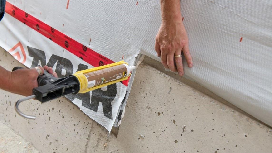 A caulking tool held by someone out of frame