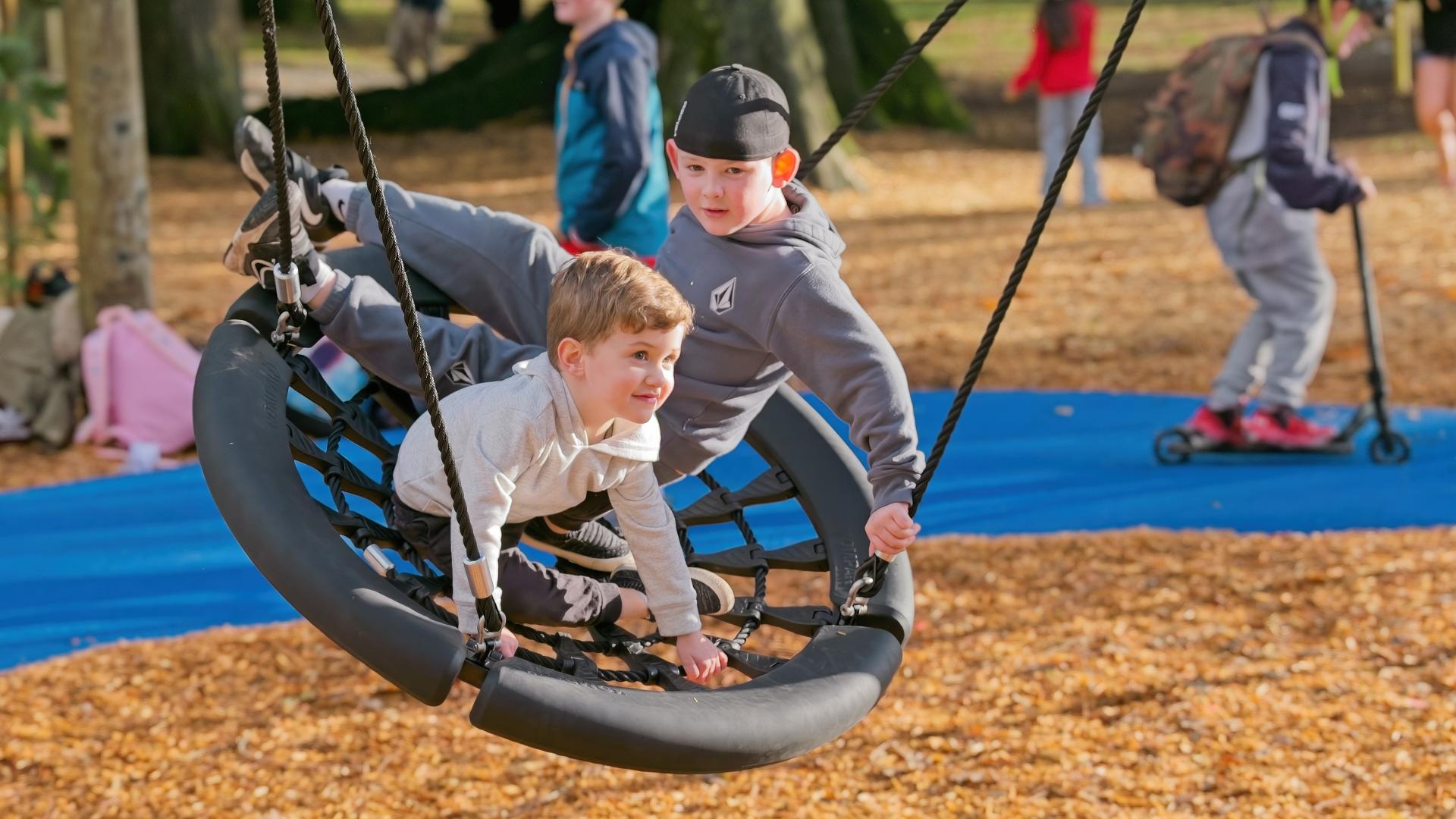 Two boys playing on a disk swing