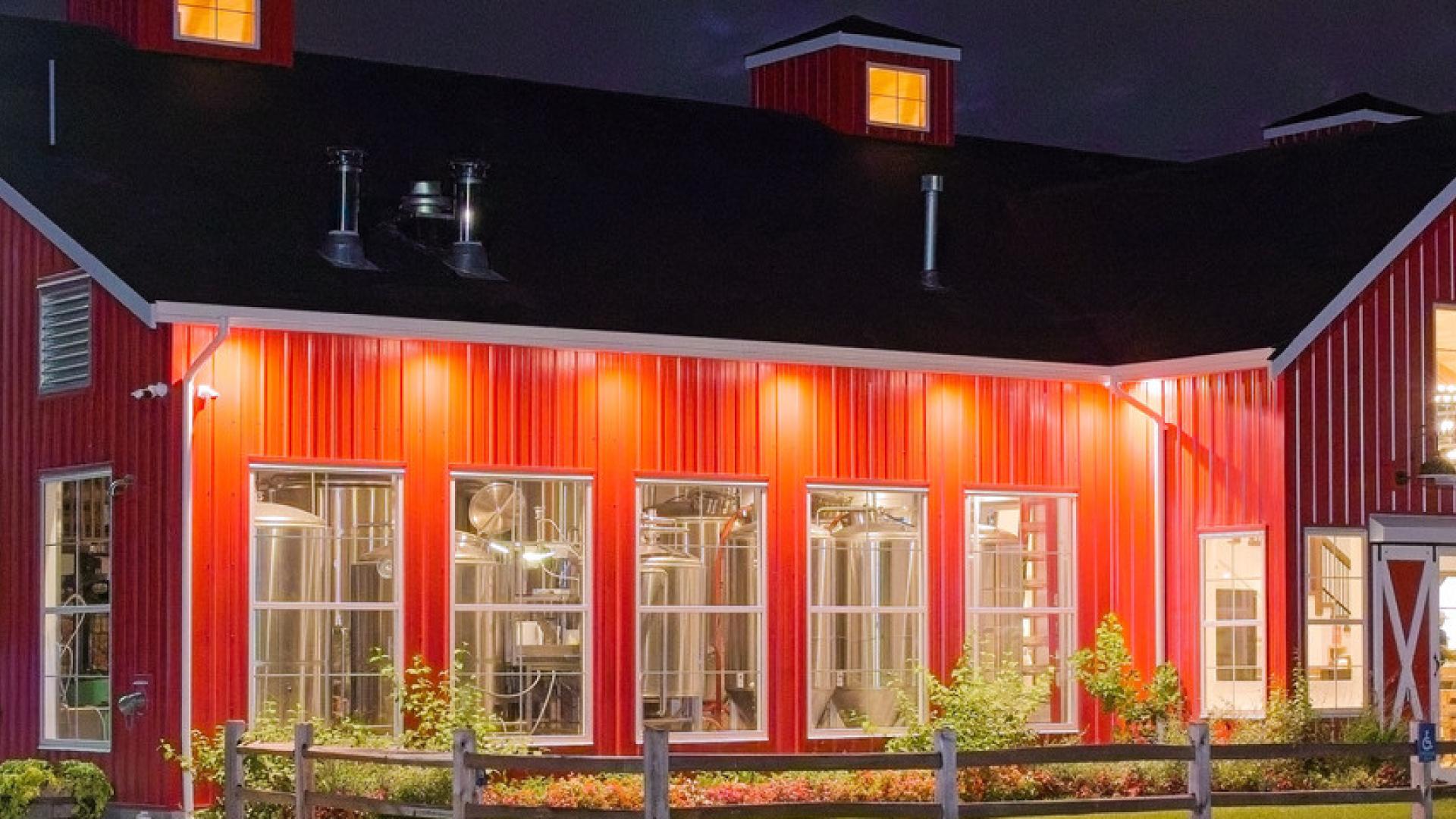 The red building of the Patch Brewery is illuminated by many exterior lights at night.