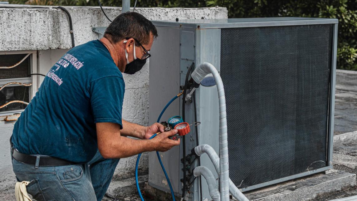 A worker installs a heating, ventilation, and air conditioning (HVAC) unit.