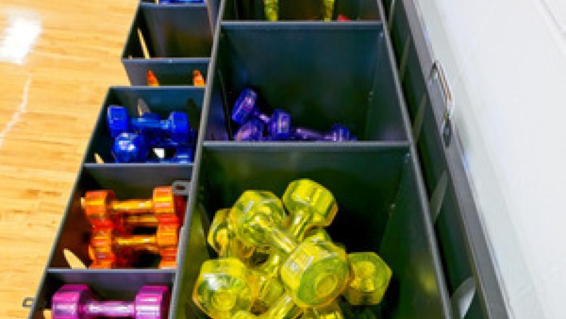 Neon weights of various sizes sit sorted by colour in plastic boxes, waiting to be used.