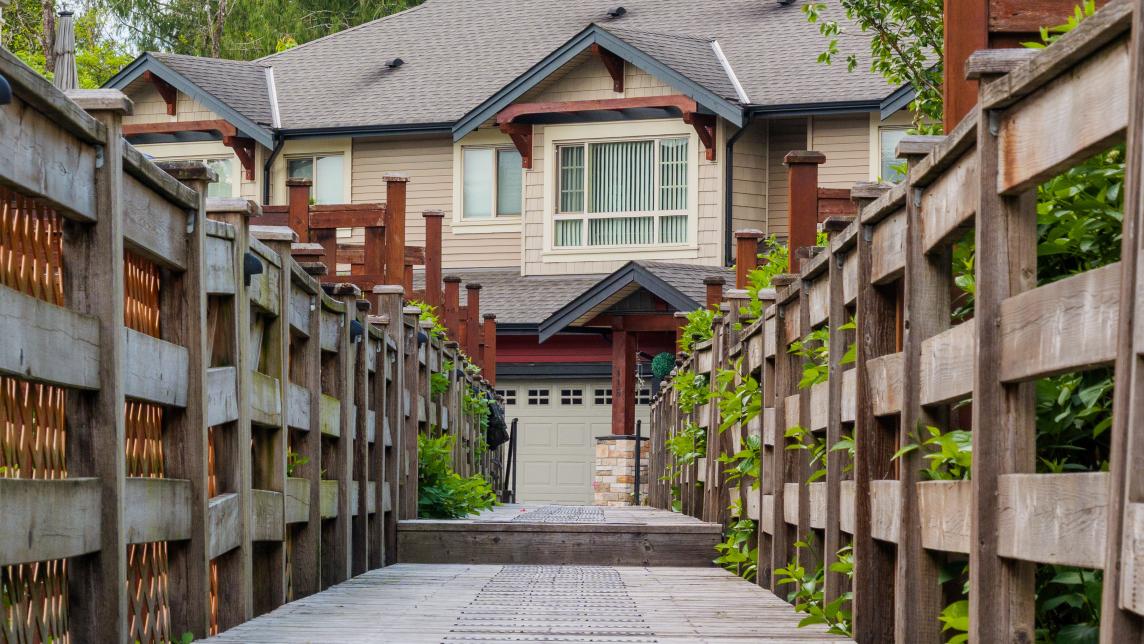 A wooden pathway leads across a gully to a set of houses.