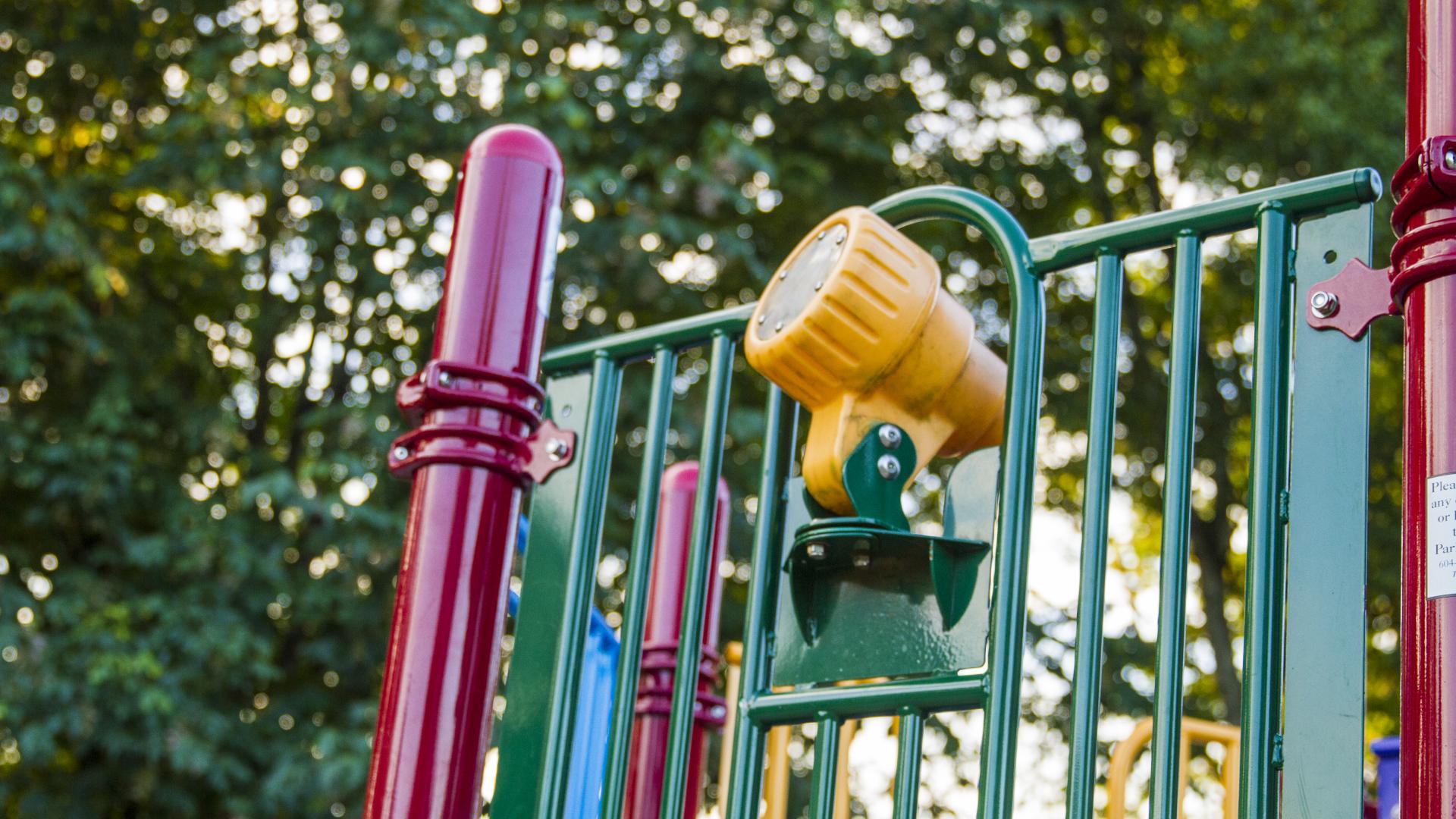 Looking up to the top of the playground, a yellow plastic telescope is mounted on the bars of the playground.