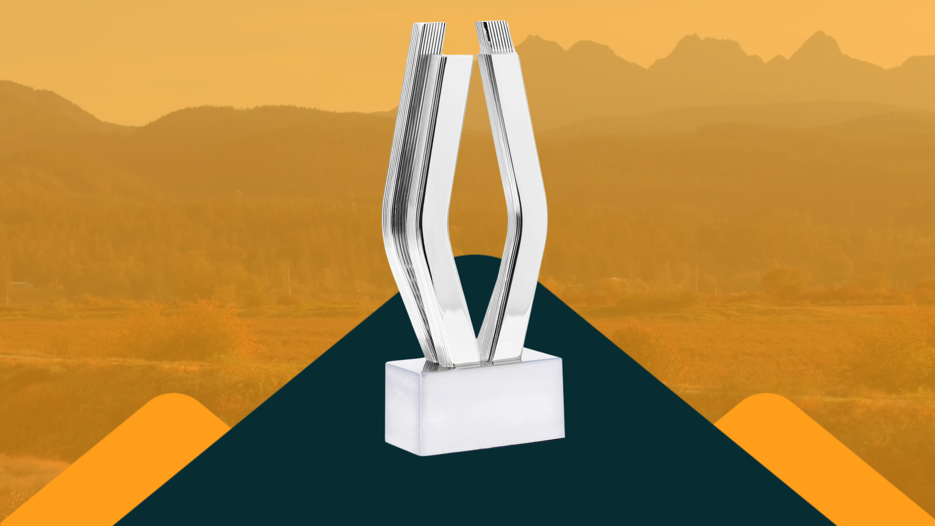 A statuette of a stylized platinum "V" stands out against a faded orange background showcasing the Maple Ridge mountain skyline.