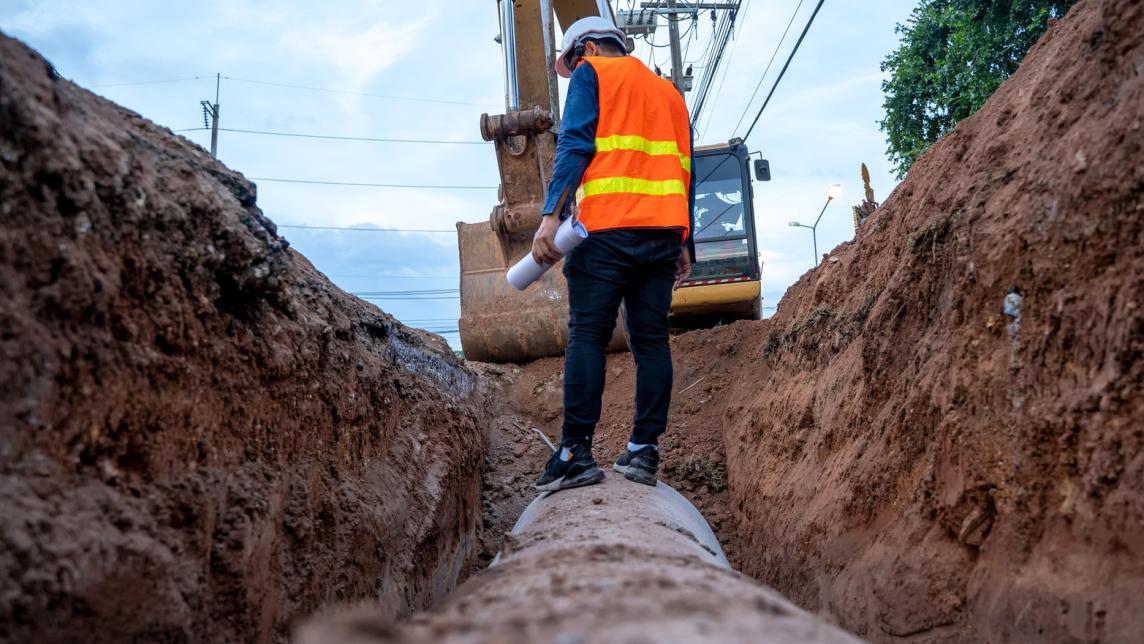 Person inspecting pipe trench under construction