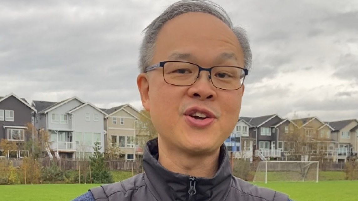 A man spreads his arms while standing in a field. The words "MapleRidge.ca/Budget" appear in front of him.
