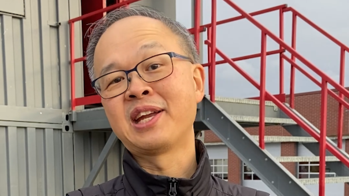 A man stands in front of a firefighting practice building. There is a caption reading "Remember, Stay informed. Stay connected".