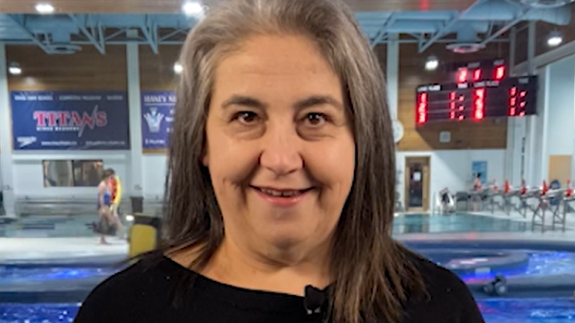 A woman smiles from inside the Maple Ridge Leisure Centre while next to the pool.