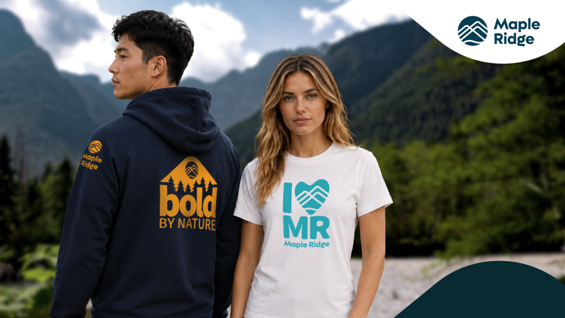 A woman wears a white shirt with I (graphic of a heart) MR written in teal across the front, while a man wears a dark hoodie with an orange pictogram of mountains and the words "bold by nature" on the back and the Maple Ridge logo on the sleeve.