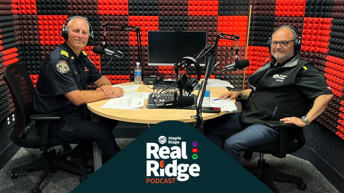 Mayor Dan Ruimy and Fire Chief Dave Samson sit across a table filled with recording equipment in a red-and-black checkerboarded room.