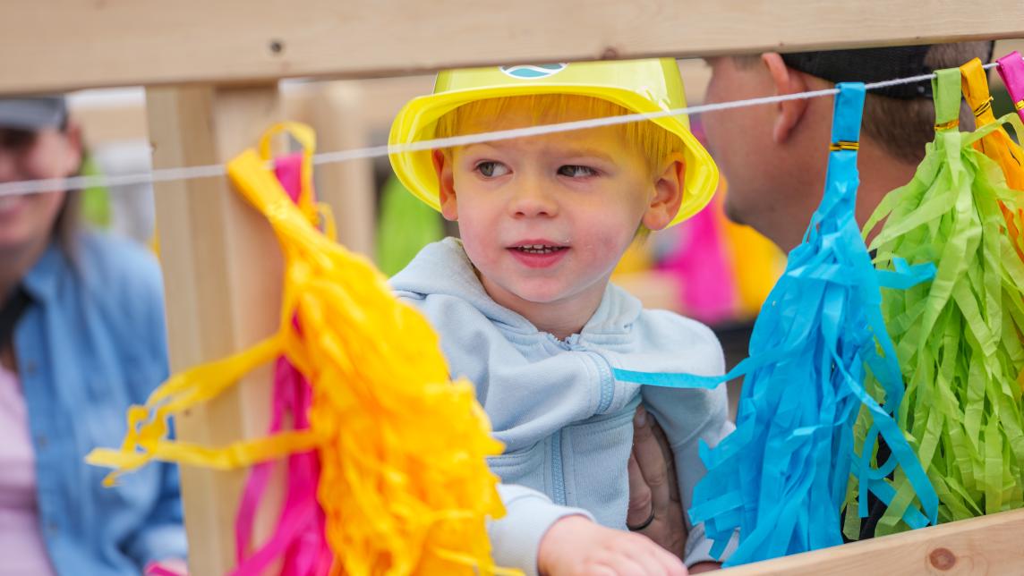 Little child wearing a yellow hat standing near decorations