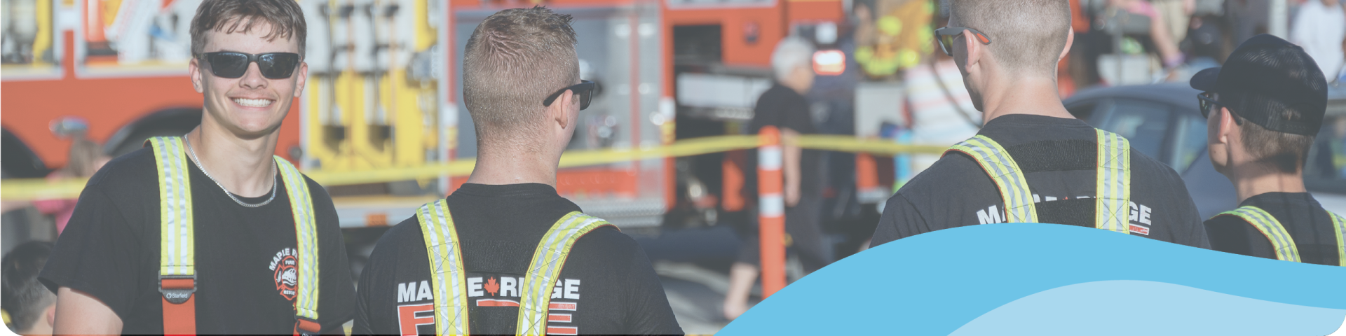 young fireman standing in front of firetrucks 