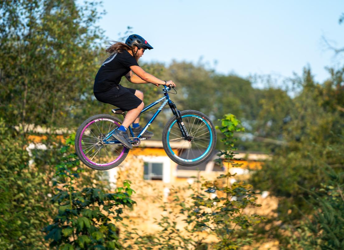 A man flies through the air from an unseen jump on his bicycle.