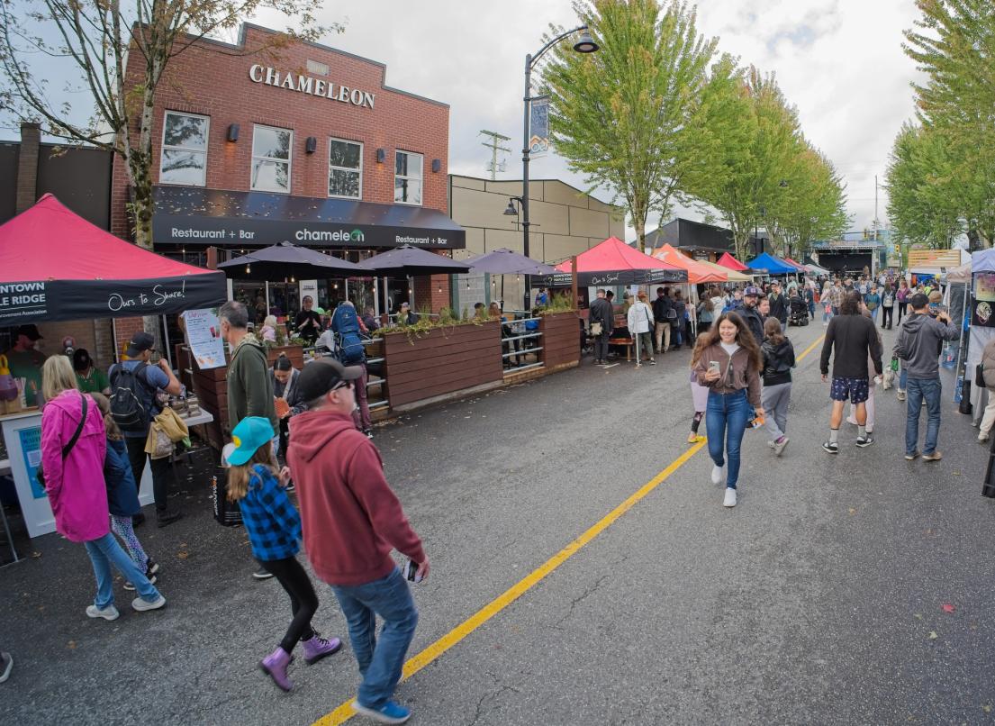 A crowd walks past the tents and storefronts at the Our Neck of the Woods festival.