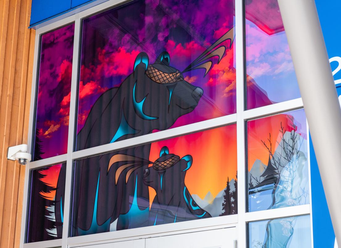 An image-based window covering depicting a mother bear and her cub being silhouetted by the sunset rests on display at the Albion Community Centre.