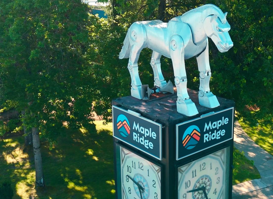 The Beast, a metal horse statue atop a clock tower, stands tall on a bright sunny day.