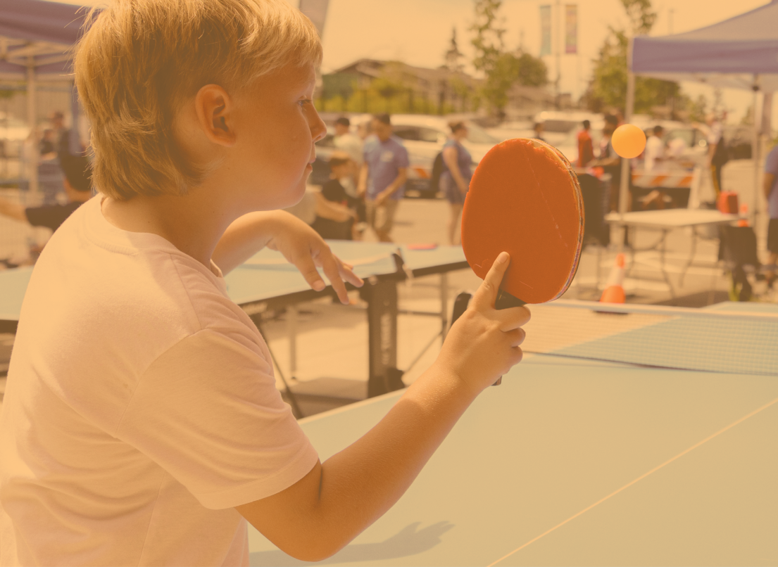 Young Boy Playing Table Tennis Outside in the Sun
