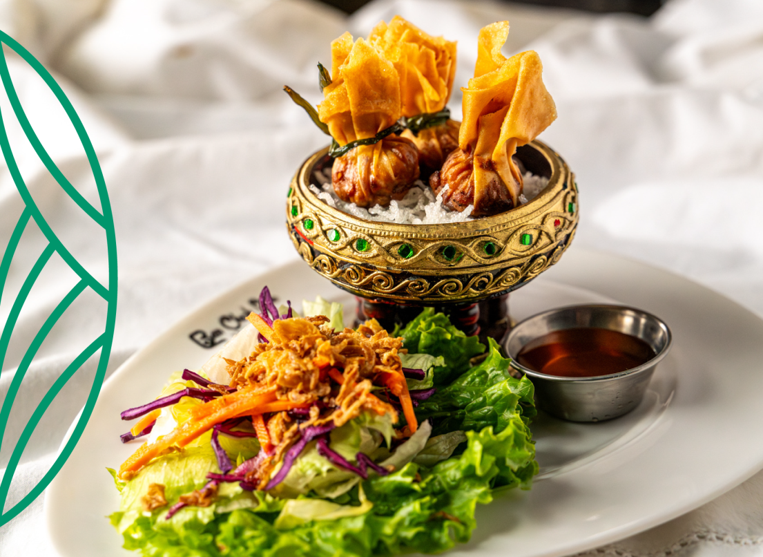 Fried dumplings on rice sit next to a bed of greens topped with carrot, and a rich amber-brown dipping sauce.