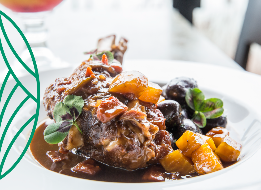 Ribs drenched in sauce, with potatoes and decorative herbs.