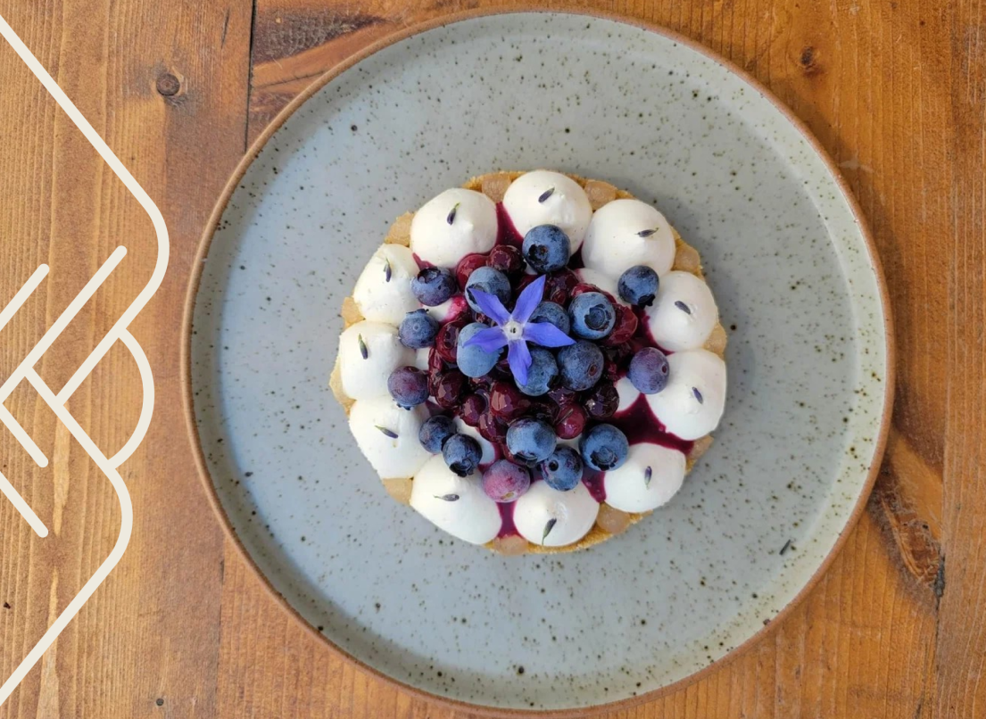 A blueberry tart topped with an edible flower.