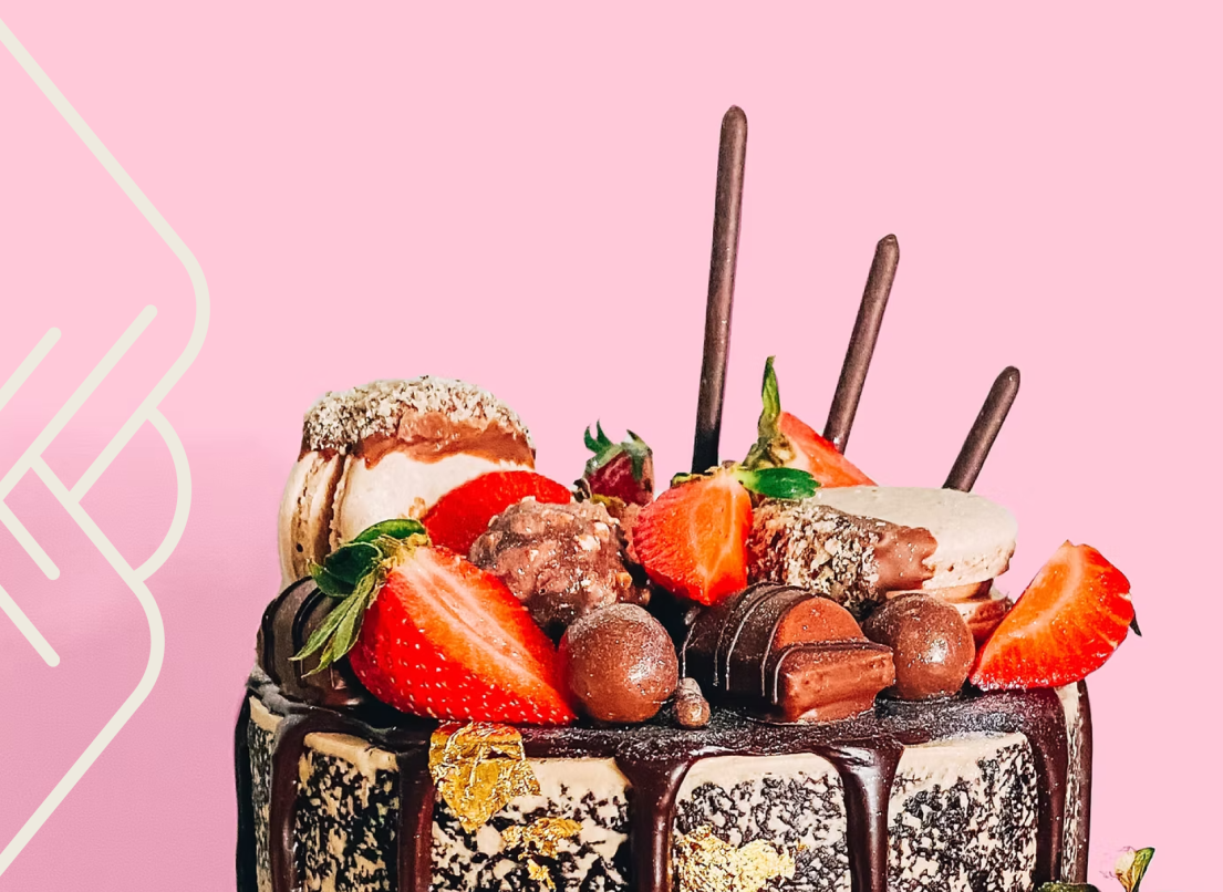 A chocolate desert in a glass cup is topped with strawberries and other red sweets.