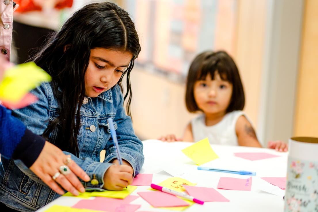 Youth Writing on Post It Notes at the Back To School Youth Social