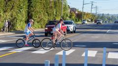 Two children on bicycles cross at a crosswalk