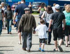 a group of people walking, with a senior man, young boy, and middle-aged man walking away from the camera