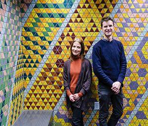 Artists standing front of their colourful mosaic work