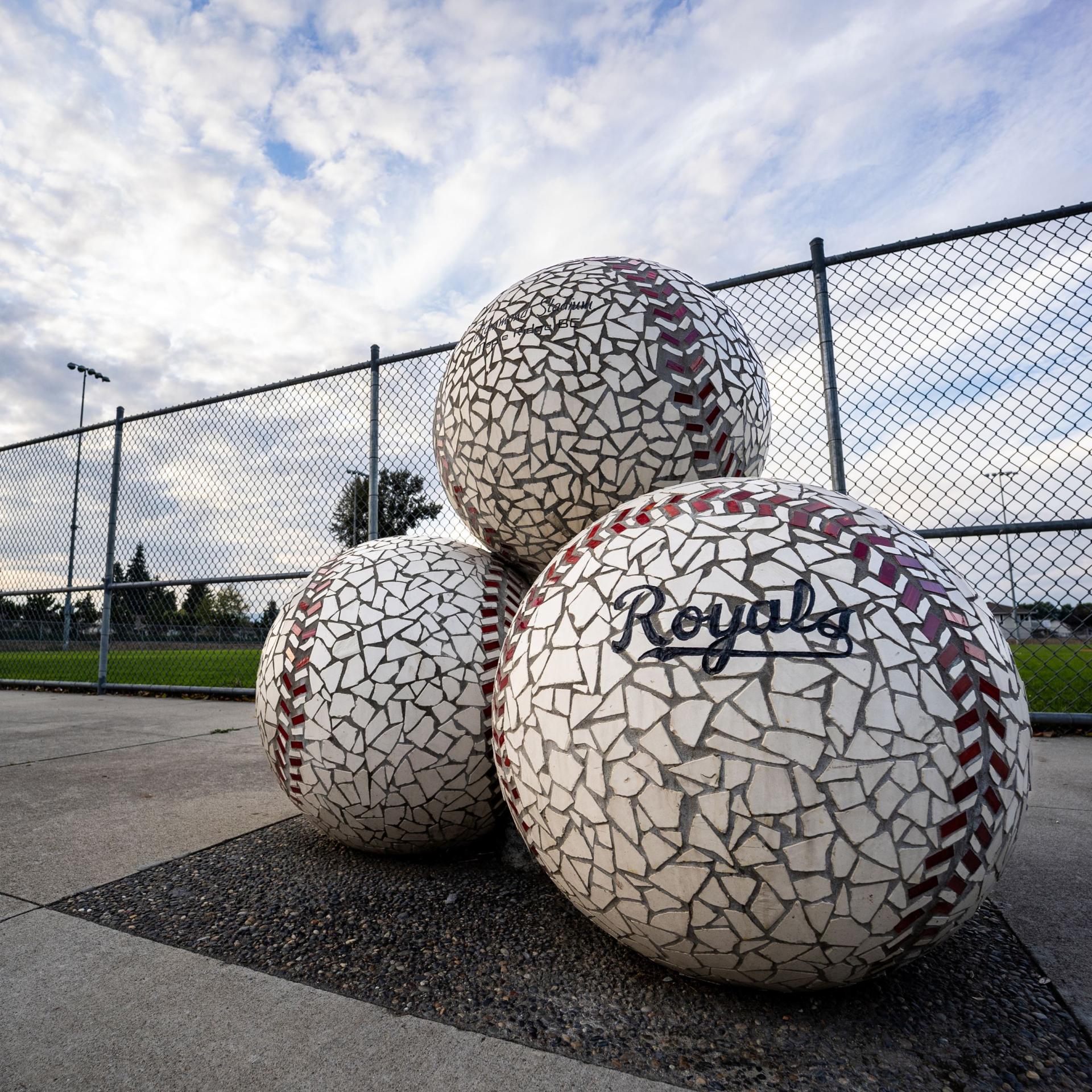 3 mosaic baseballs stacked in front of a ball park.