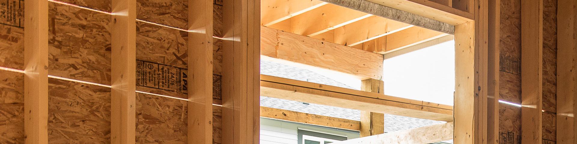 Light streams in through the wooden frame and window of a house mid-construction.