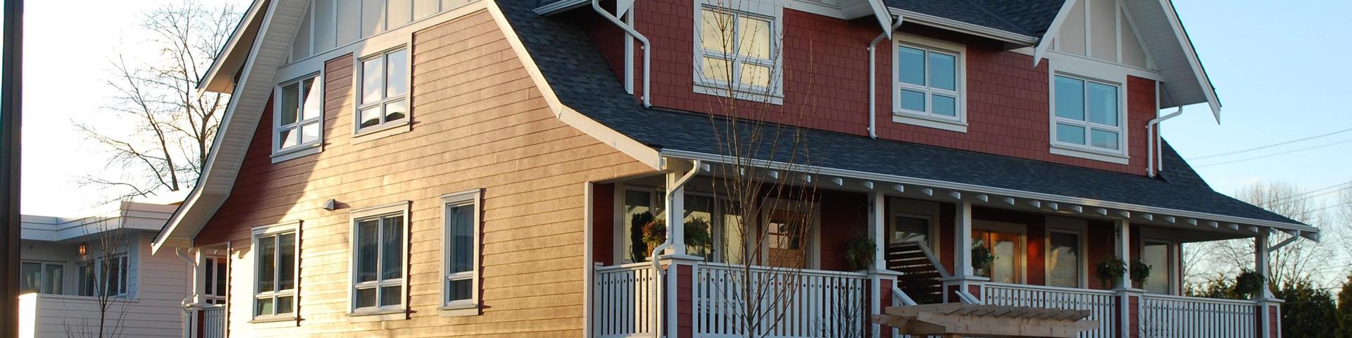 A red house with white trim is bathed in light from the sunset.