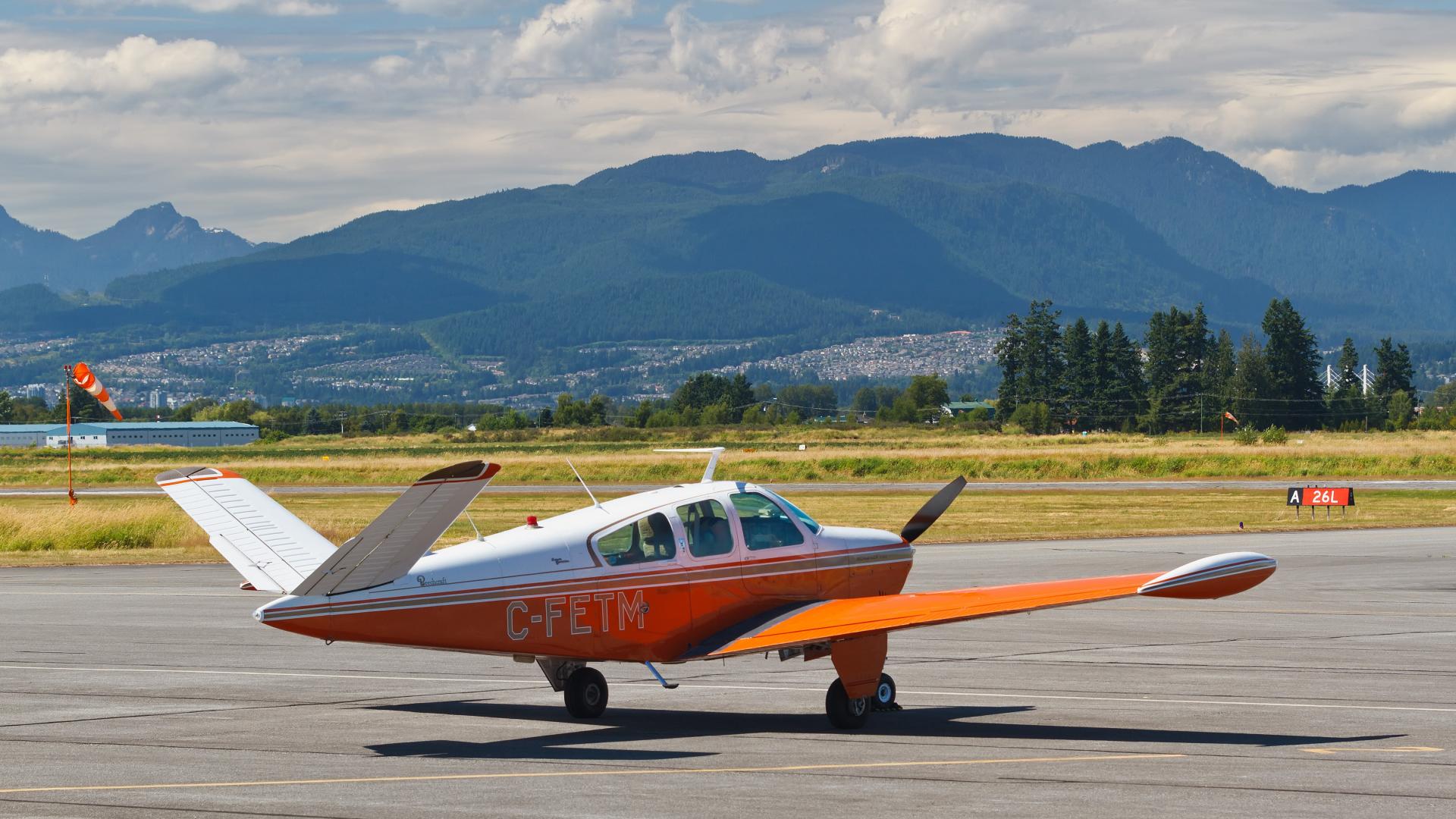 A red and white propellor plane sits on the tarmac at Pitt Meadows Airport.